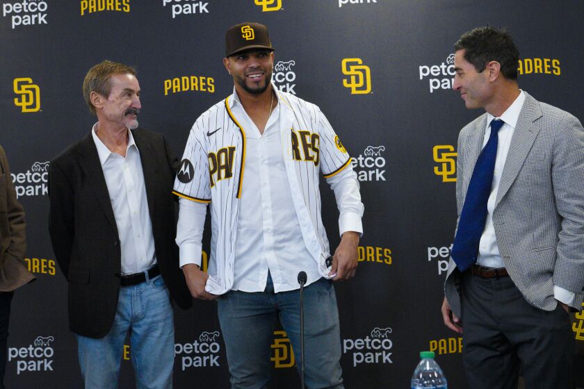 San Diego, CA - December 09: At press conference held at Petco Park on Friday, Dec. 9, 2022 in San Diego, CA., Xander Bogaerts tries on his Padres jersey with Peter Seidler (l) and A. J. Preller (r) watching. (Nelvin C. Cepeda / The San Diego Union-Tribune)