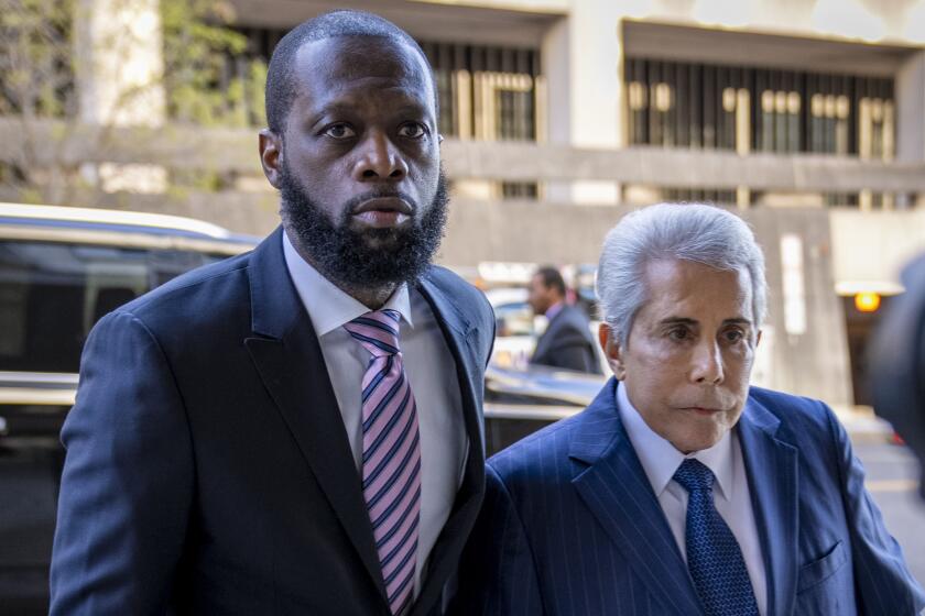 Fugees rapper Pras enters court with his lawyer