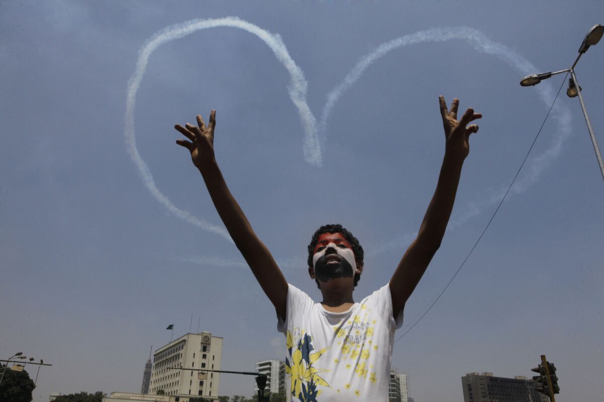 An Egyptian protester in Cairo flashes the victory sign against a backdrop of military aircraft vapor trails in the shape of a heart. Wednesday's military coup ousted President Mohamed Morsi and his Muslim Brotherhood, but the role of Islam in government remains a divisive issue.