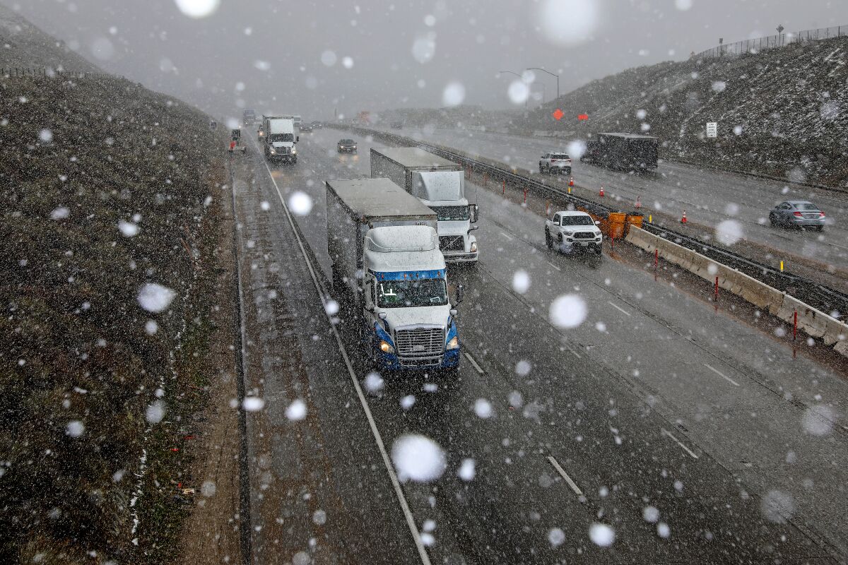 Snow flurries fall while tractor trailers and automobiles travel along Interstate 5 at the Tejon Pass along the Grapevine.