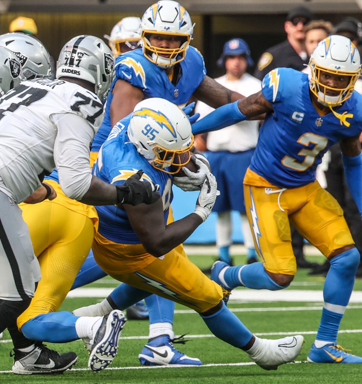     Chargers defensive tackle Poona Ford (95) intercepts a pass from teammate Khalil Mack to secure the win over the Raiders.