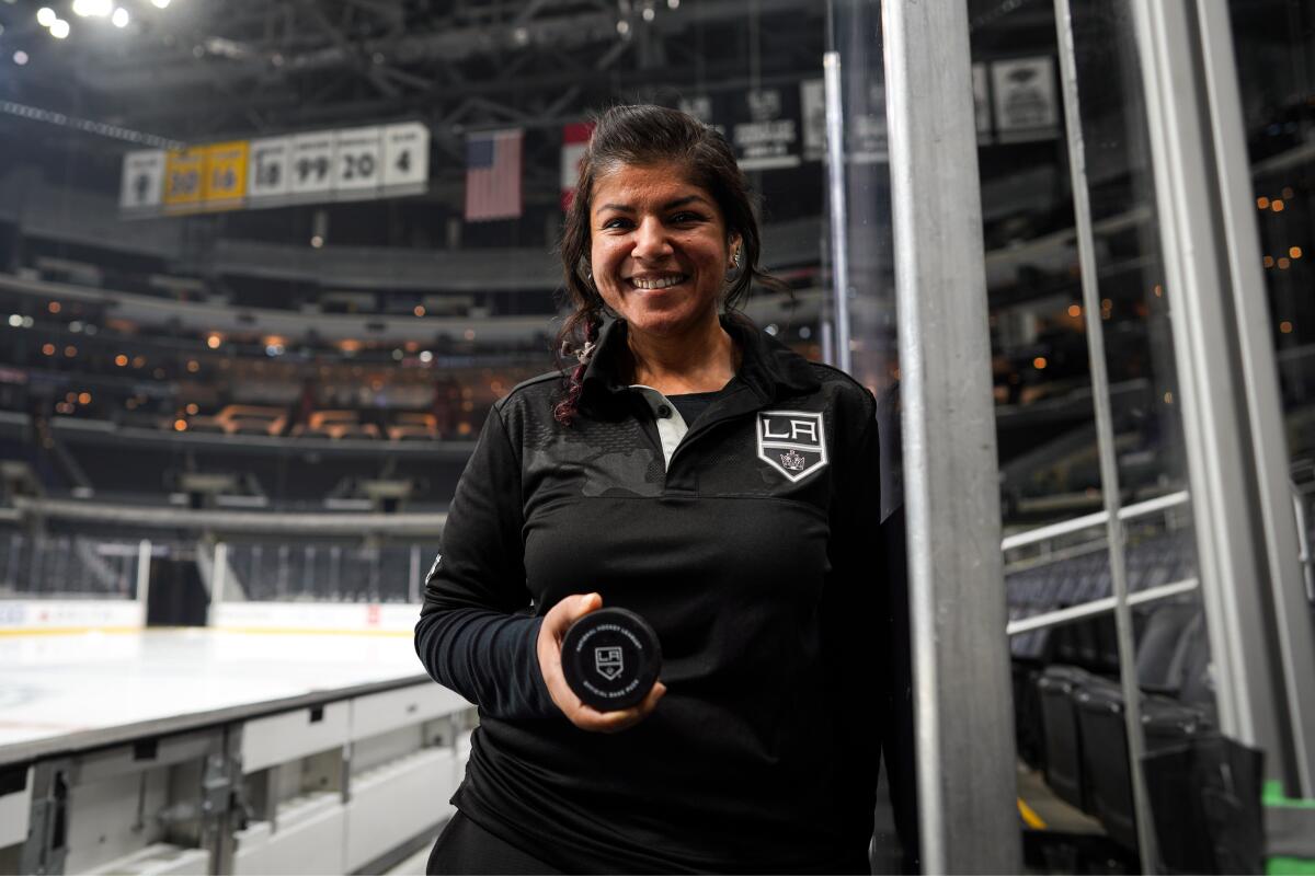 Aisha Visram stands on the Kings' bench holding a puck at Crypto.com Arena.