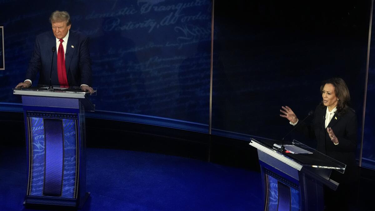 A man and a woman stand behind lecterns on a stage.