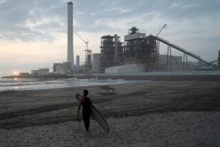 FUKUSHIMA, JAPAN - AUGUST 20: A surfer walks on the beach in front of the Hirono Thermal Power Station during the Iwasawa Surfing Games at Iwasawa beach on August 20, 2023 in Naraha, Fukushima Prefecture, Japan. A total of 189 surfers gathered on the beach, about 20 km away from the crippled Fukushima Daiichi nuclear power plant, for the competition. The competition is being held for the first time in 13 years after the nuclear disaster following the March 11, 2011 earthquake. (Photo by Tomohiro Ohsumi/Getty Images)