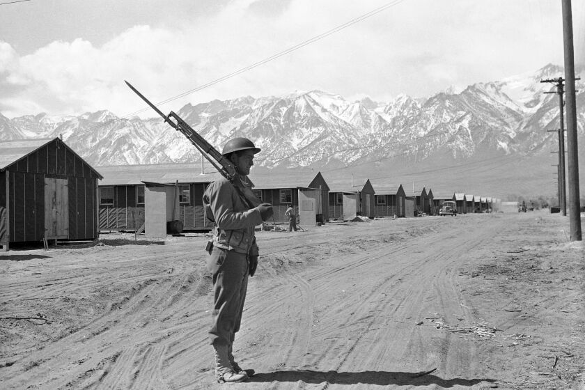 File - In this May 23, 1943, file photo, an American soldier guards a Japanese internment camp at Manzanar, Calif. A human skeleton retrieved from California’s second-highest mountain, Mount Williamson, in October 2019, may be the remains of a Japanese-American man who died in 1945 as part of a fishing party from the Manzanar internment camp. The Inyo County Sheriff’s Department says that is among the possibilities being investigated after the bones were discovered Oct. 7 by two hikers. (AP Photo/File)