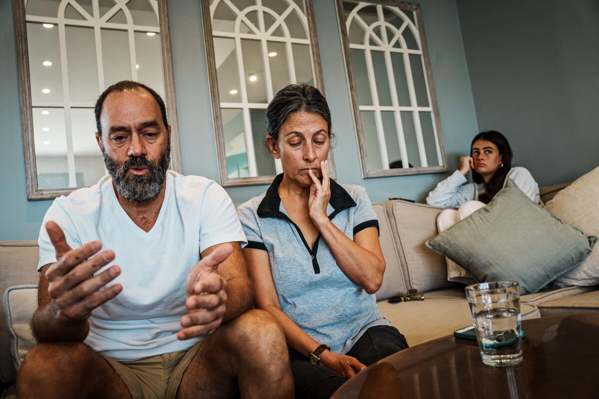 A man and woman sit on their couch with their daughter.