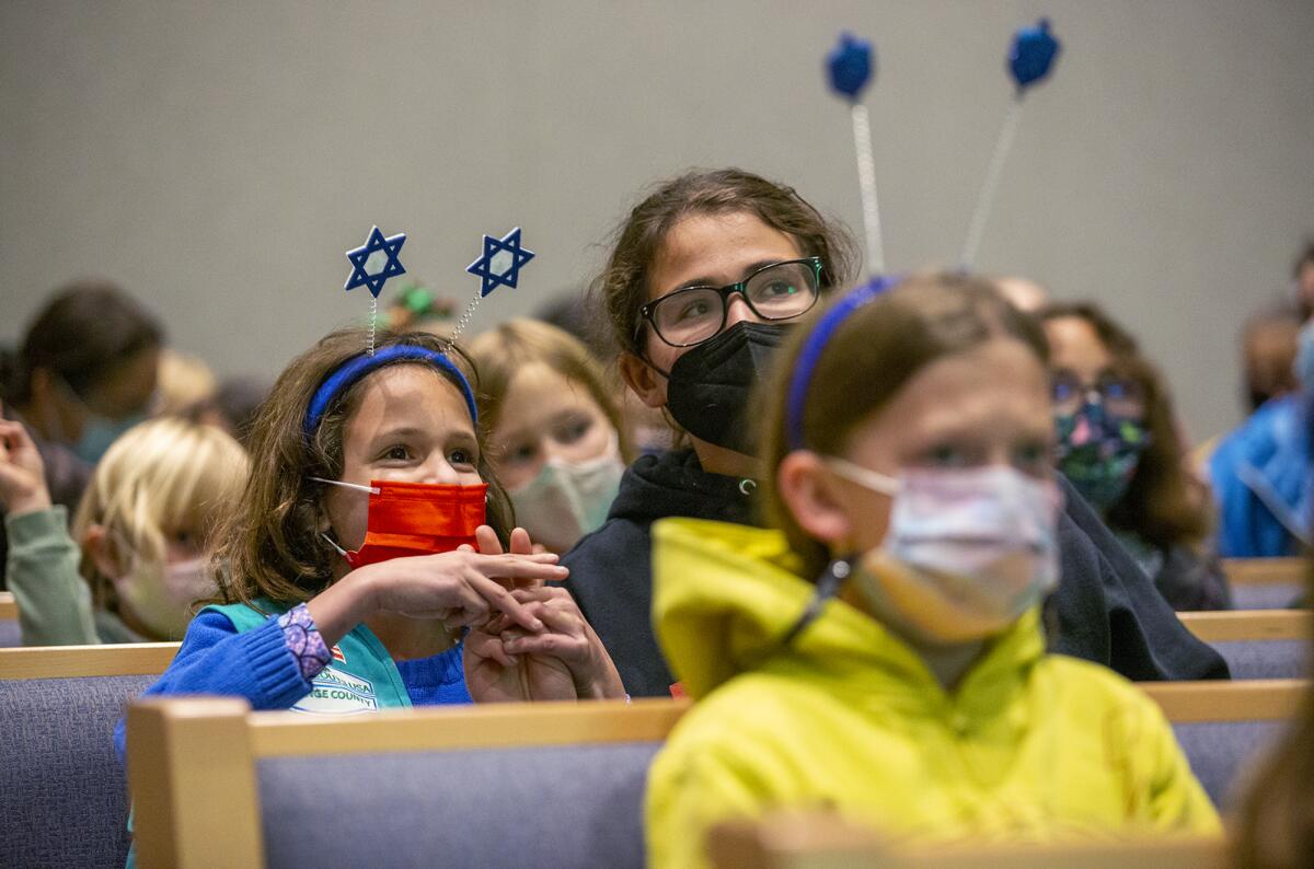 Coral Kahana, left, and her sister Claudia listen to Rabbi Sarah DePaolo during a Hanukkah event Thursday night.