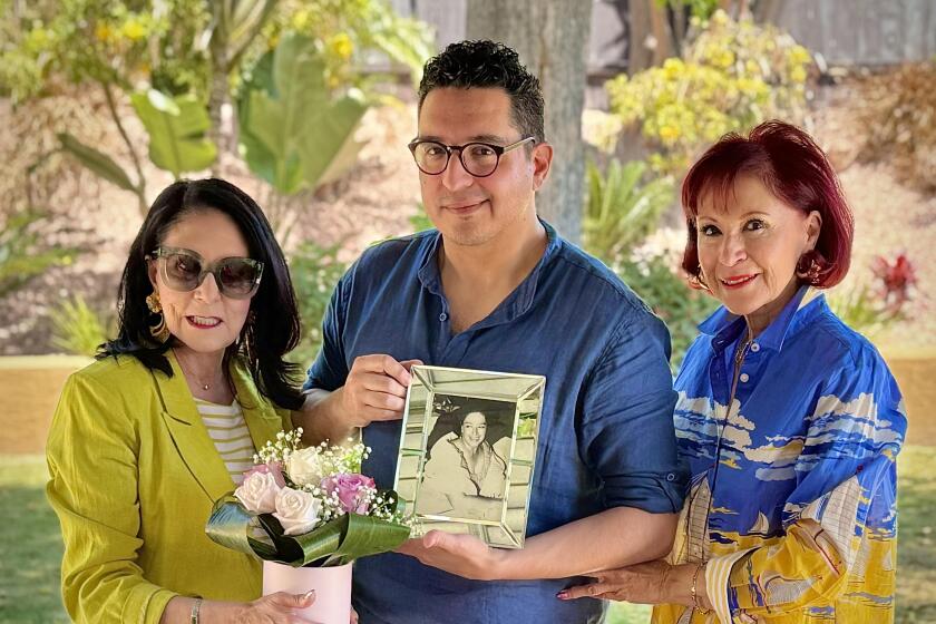 Jordan Jacobo holding a photo of my grandmother (center) with his mother (left) and his aunt (right)