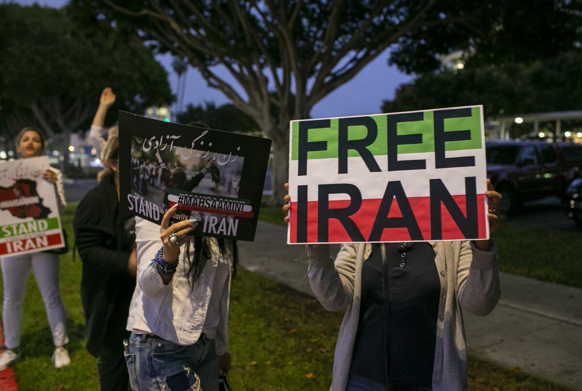  Iranian women holds signs during a protest against the Iranian government outside Costa Mesa City Hall on Friday.