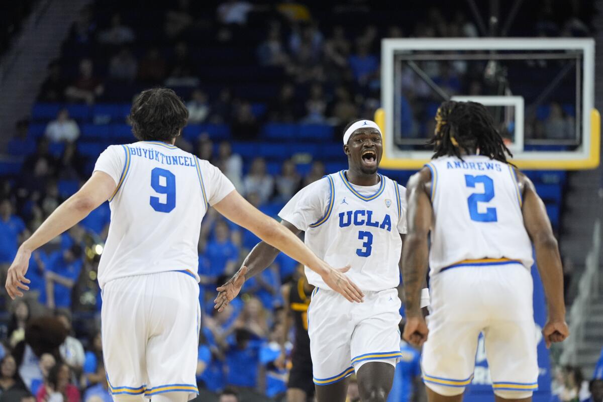 Three UCLA basketball players celebrate a dunk against Arizona State