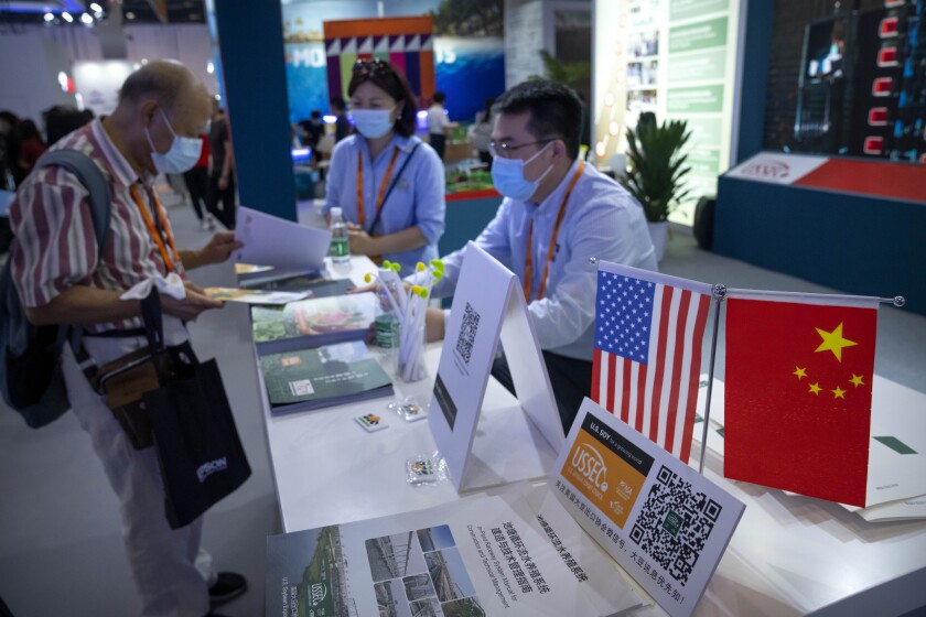 Staff members stand near American and Chinese flags at a booth for the U.S. Soybean Export Council at the China International Fair for Trade in Services (CIFTIS) in Beijing, Friday, Sept. 3, 2021. China's envoy to trade war talks with Washington expressed concern about U.S. tariffs on Chinese imports during a phone call Tuesday, July 5, 2022, with Treasury Secretary Janet Yellen, the Ministry of Commerce announced, but it gave no indication of progress toward resolving an array of conflicts. (AP Photo/Mark Schiefelbein)