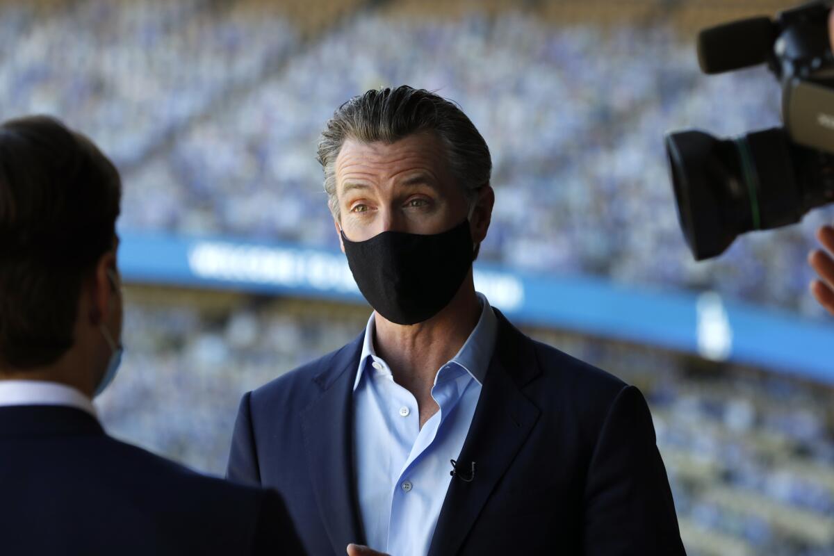 Gov. Gavin Newsom talks with the media at Dodger Stadium.