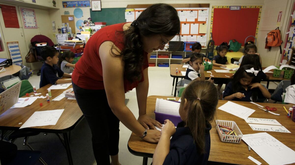 Kindergarten teacher Claudia Garcia helps Michelle Lopez at a Magnolia charter school in Northridge in 2014.