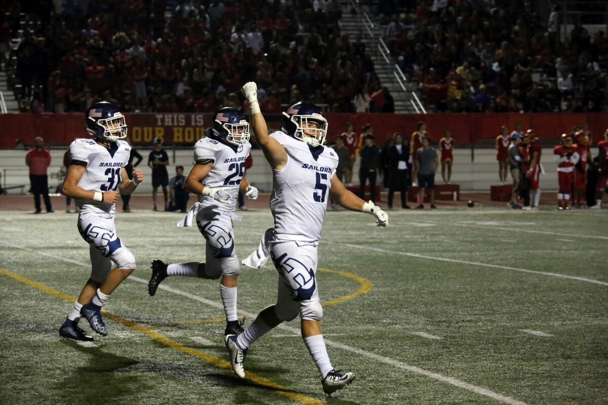 Newport Harbor's Johnny Brigandi celebrates with his teammates after recovering the ball during Newport Harbor's game against Woodbridge on Friday.