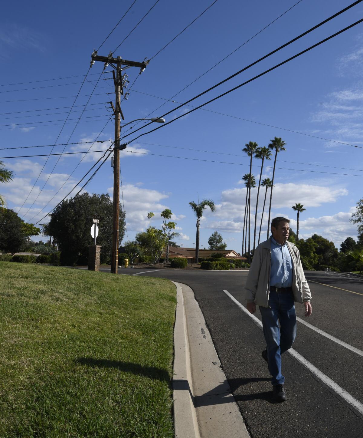 Jose Reynoso, president of the Alvarado Estates Community Assn., walks by a utility pole and power lines on Yerba Santa Drive inside Alvarado Estates in San Diego. City Atty. Mara Elliott says the neighborhood is ineligible to have its utilities undergrounded because it's a gated community.