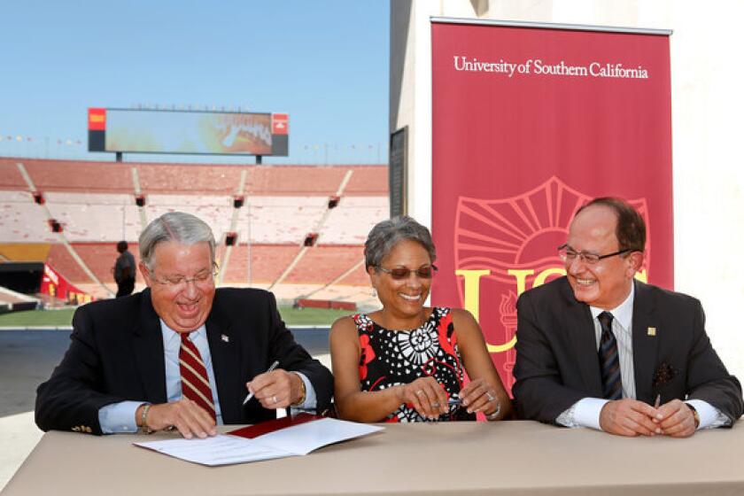 From left, Los Angeles County Supervisor Don Knabe, the president of the Coliseum Commission; Fabian Wesson, chair of the California Science Center board of directors; and USC President C.L. Max Nikias during a ceremonial signing of a lease giving USC control the Los Angeles Memorial Coliseum, seen in the background.