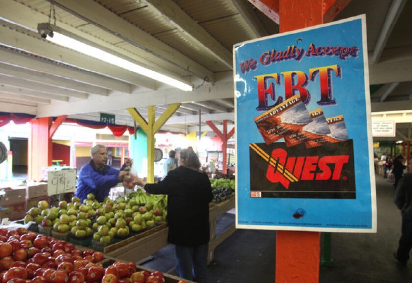 A sign announces the acceptance of food stamps at a farmers market in Roseville, Calif.