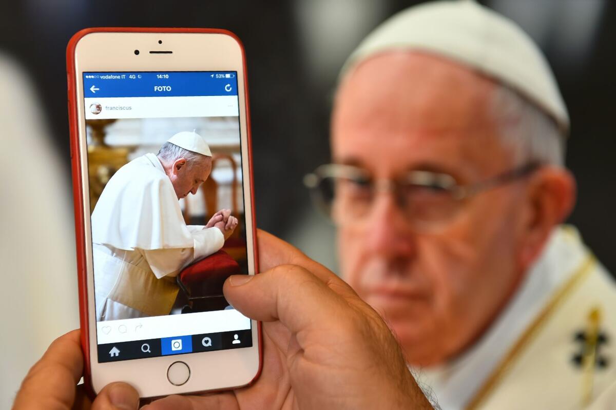 A man looks at the Instagram account of Pope Francis, which launched on March 19, 2016.