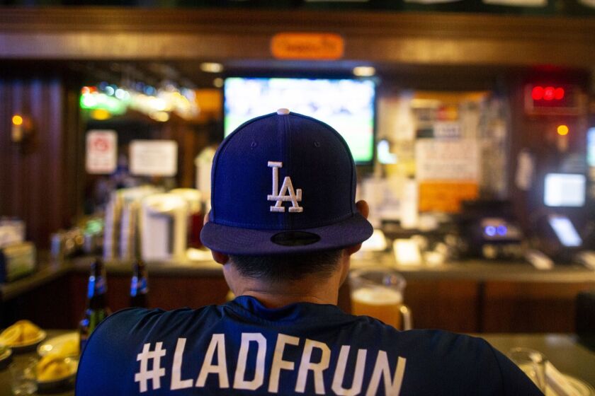 LOS ANGELES, CALIF. - OCTOBER 04: A man wearing Dodger gear sits at the bar as he and other people watch the first game of the NLDS between the Los Angeles Dodgers and the Atlanta Braves at OB Bear in Koreatown on Thursday, Oct. 4, 2018 in Los Angeles, Calif. (Kent Nishimura / Los Angeles Times)