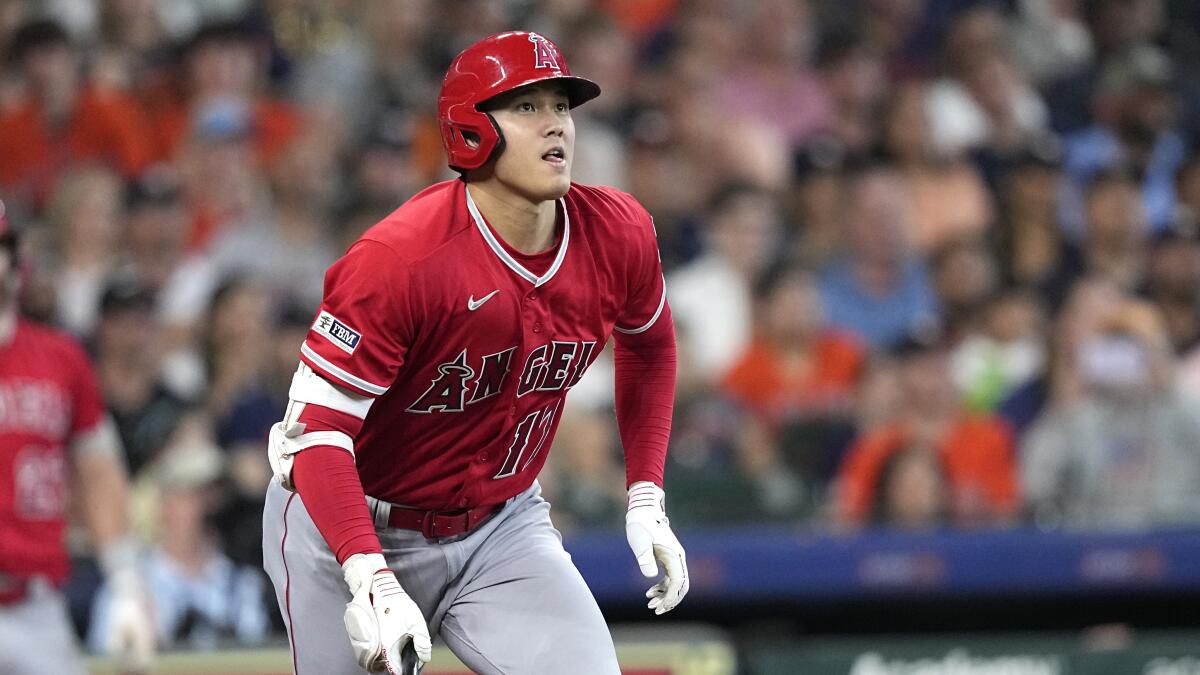 Shohei Ohtani leans forward, starts to drops his bat and watches his double against the Houston Astros.