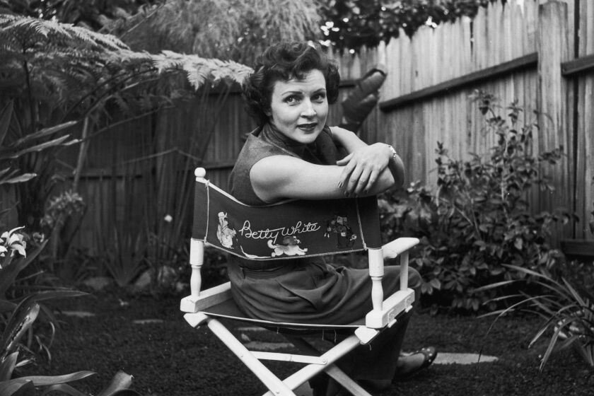 circa 1956: American actor Betty White sits in a canvas chair with her name written on the back, looking over her shoulder in a backyard garden. (Photo by Hulton Archive/Getty Images)
