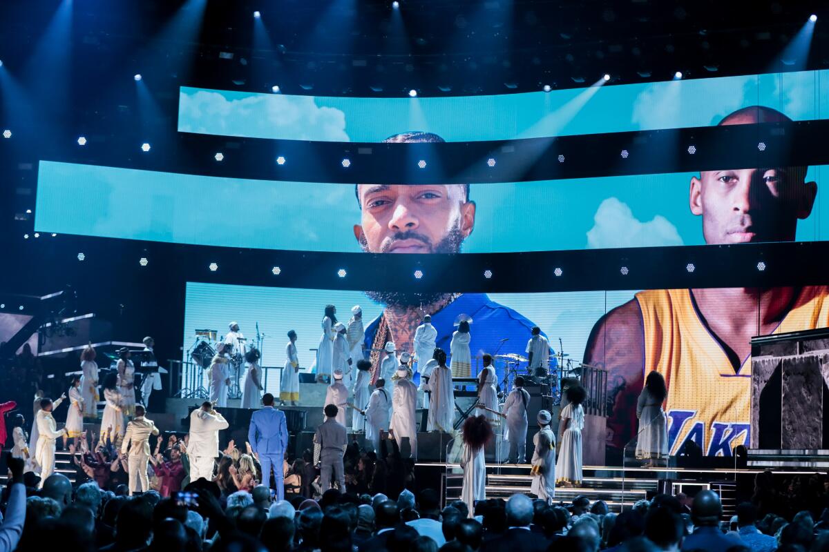 A tribute to Nipsey Hussle and Kobe Bryant is displayed as YG, John Legend, DJ Khaled, Meek Mill, Roddy Ricch, Kirk Franklin and others stand on stage at the Grammy Awards on Sunday.