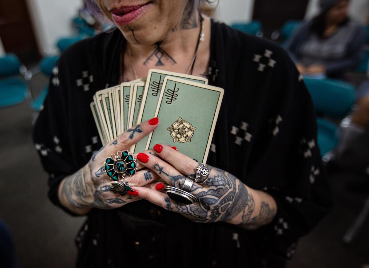 Tarot cards in a person's tattooed hands. 