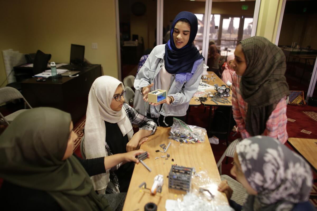 During a practice in September, coach Zaina Siyed explains what team members need to transport a shark toy with their Lego robot. All the team members wear hijabs inside the mosque where they practice.