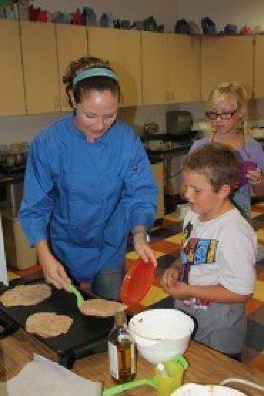 Peter watches in anticipation as Fernanda Larson serves up student-made pita bread in her Cook for Thought class after-school at Del Mar Hills.