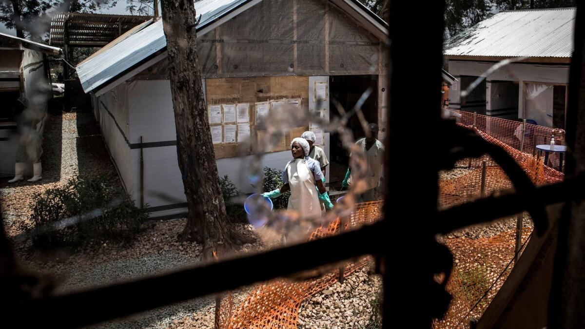 Health workers are seen through a bullet hole left in the window of an Ebola treatment center attacked early Saturday in Butembo in eastern Congo, resulting in the death of a police officer.