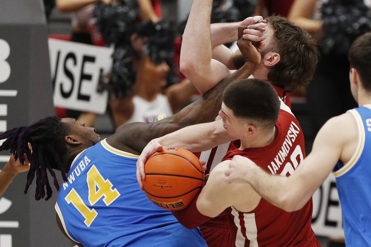 Washington State forveti Andrej Jakimovski (ortada), UCLA forveti Kenneth Nwuba'nın yanında ribaunt alıyor.