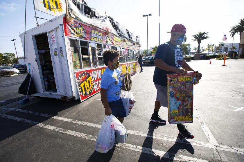HAWTHORNE, CA - JUNE 29: Jaden Veal, 7, left, and his father James Veal, right, both of Hawthorne purchase fireworks five days prior to the 4th of July at a fireworks stand on Monday, June 29, 2020 in Hawthorne, CA. (Francine Orr / Los Angeles Times)