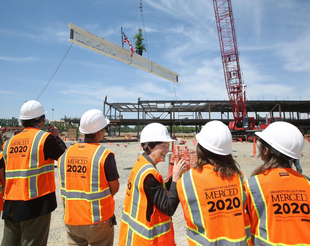UC Merced Chancellor Dorothy Leland and student leaders watch the final beam of a building get positioned into place in Merced, Calif., on May 7.