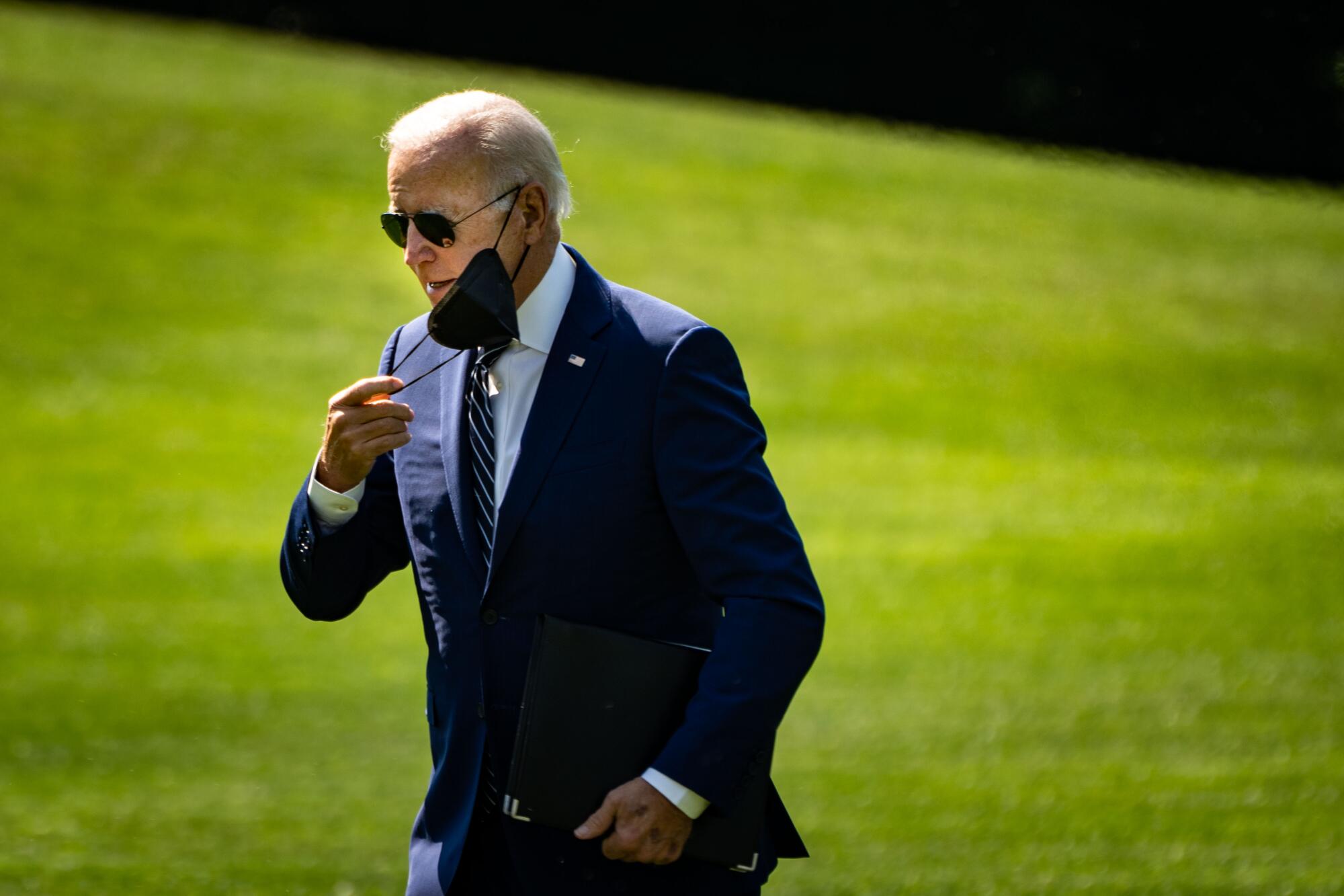 President Biden takes his mask off after disembarking from Marine One