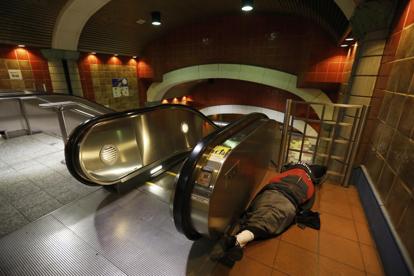 A person sleeps beside an escalator at the Hollywood/Vine Metro station. The 2018 Greater Los Angeles Homeless Count is tallying people around the city, including those sleeping near Metro stations and on trains.