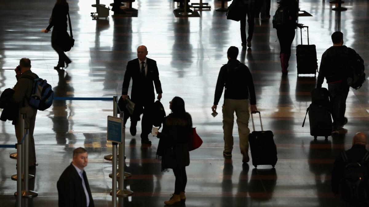 Travelers arrive at Ronald Reagan Washington National Airport. Business travel may be hurt by the travel ban from six mostly Muslim countries, according to a business travel group.