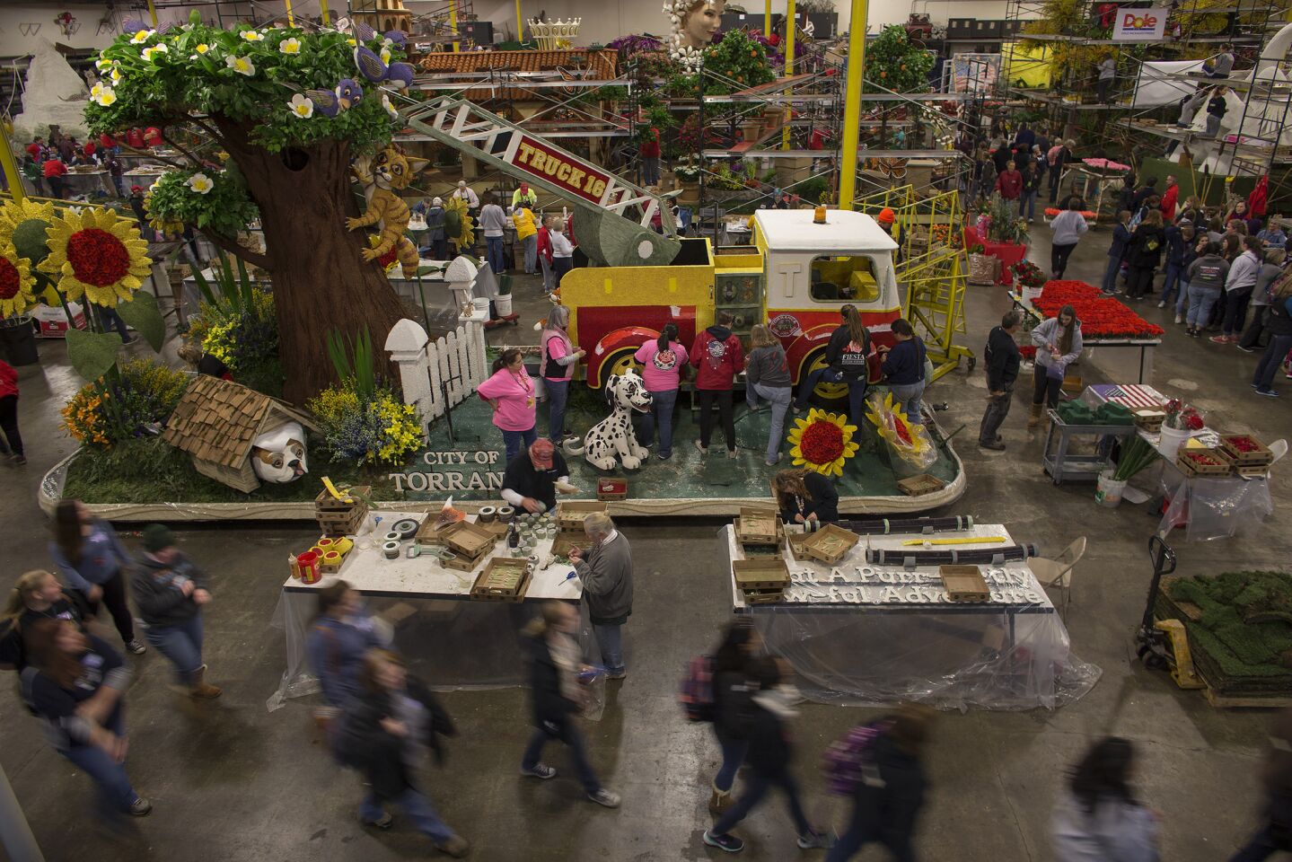 Workers and volunteers scramble to finish Rose Parade floats in a warehouse in Irwindale on Wednesday.