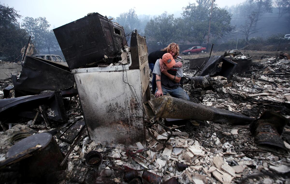 Sheri Marchetti-Perrault and James Benton embrace as they sift through the remains of their home 