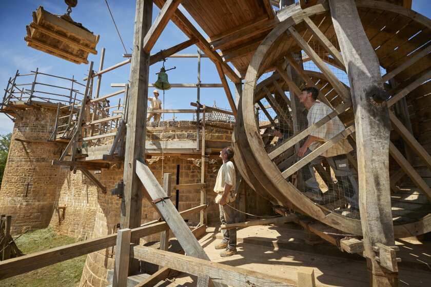 Masons drive the treadwheel crane at Guedelon medieval castle project, a back-to-the-future project re-creating a 13th century castle from scratch in the heart of Burgundy, central France.