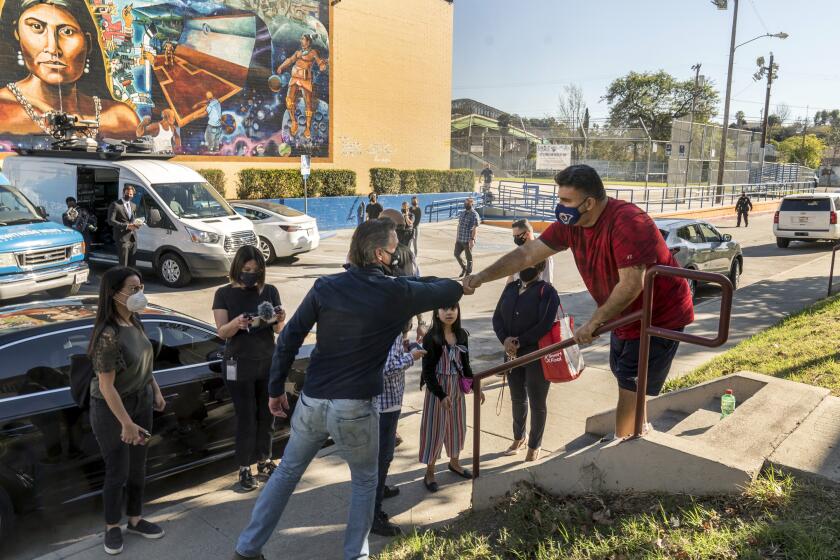 FILE - In this Feb. 21, 2021, file photo, California Gov. Gavin Newsom, front left, greets resident Israel Ortiz after Newsom visited a mobile vaccination site at Ramona Gardens Recreation Center in Los Angeles. As Newsom faces a likely recall, Latino advocates say engaging their communities and providing a more robust response to the pandemic could be keys to his survival. (AP Photo/Damian Dovarganes, File)