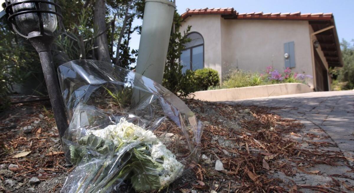 A bouquet of flowers is placed in front of the Rancho Santa Fe home where two women and a teenage girl were found dead Monday.