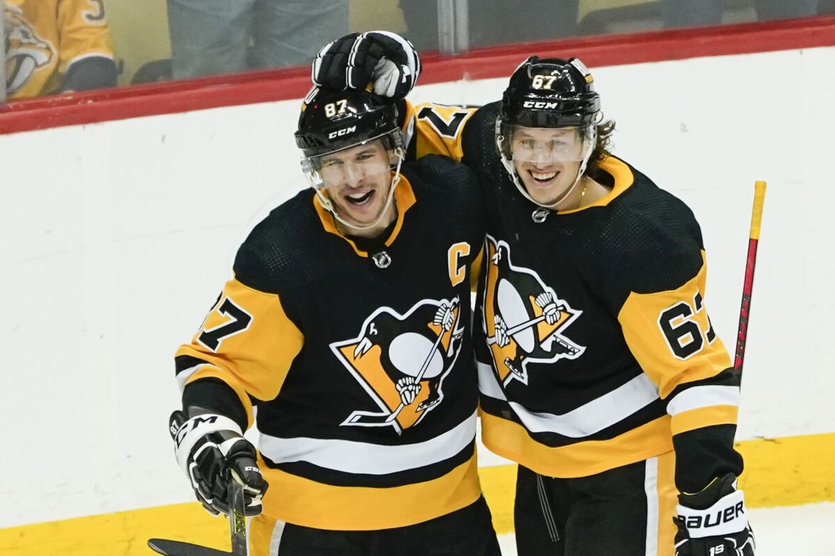 Pittsburgh Penguins' Sidney Crosby, left, celebrates with Rickard Rakell (67) after scoring the game winning goal against the Nashville Predators during the overtime period of an NHL hockey game, Sunday, April 10, 2022, in Pittsburgh. The Penguins won 3-2. (AP Photo/Keith Srakocic)