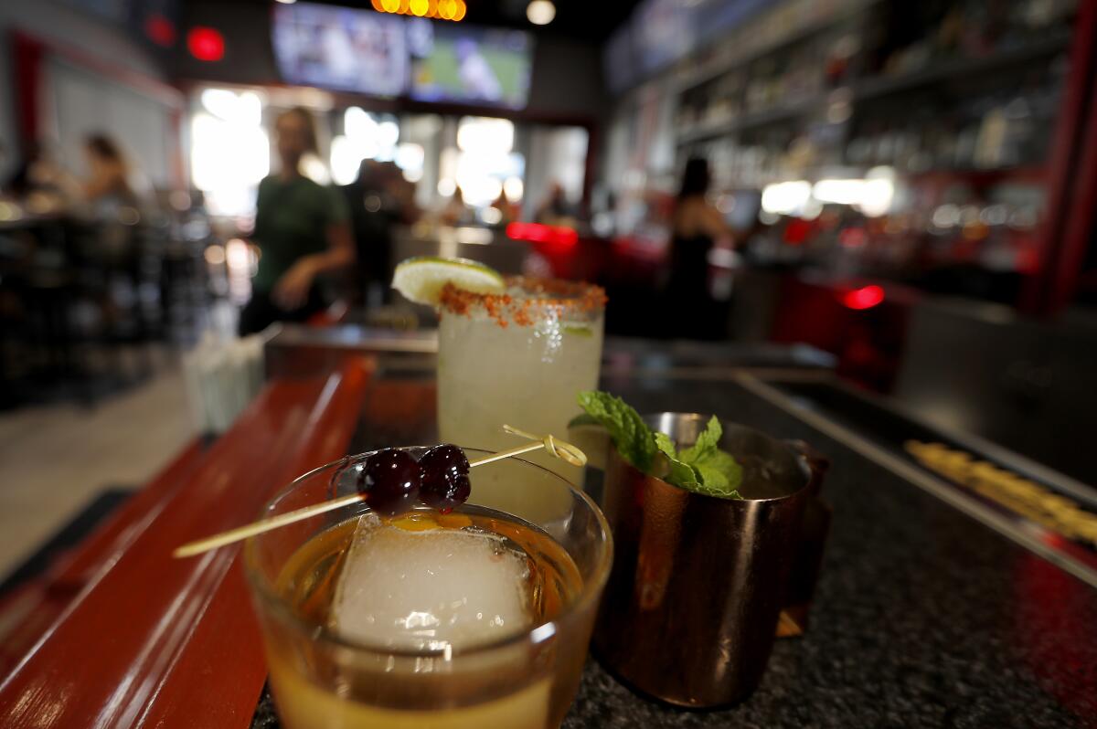 Three alcoholic drinks on a bar counter.