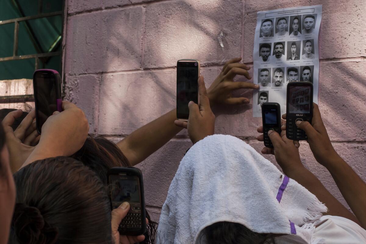 Familiares de las personas asesinadas por las pandillas en El Salvador le toman fotos a las víctimas.