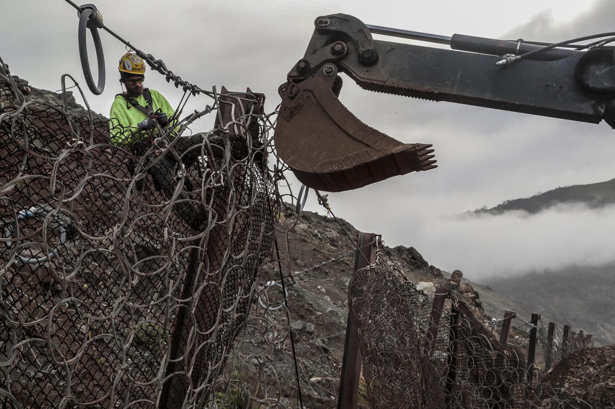 A man works behind fencing.