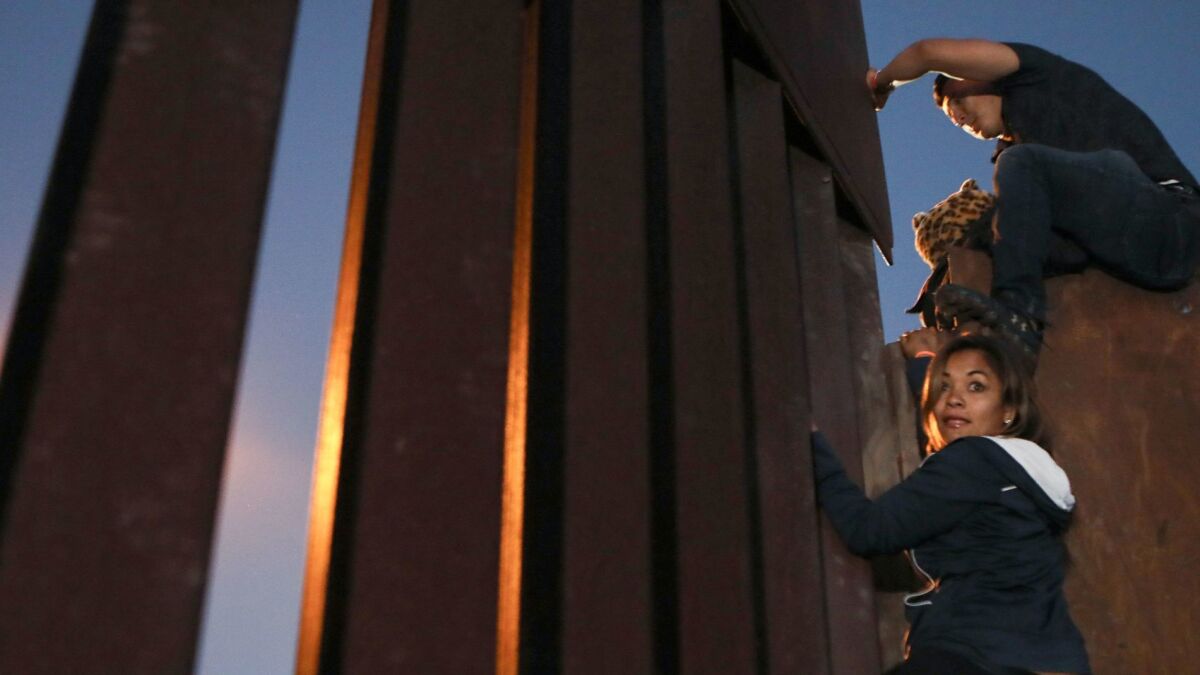 Members of the 'migrant caravan' climb over the U.S.-Mexico border fence on Dec. 3, 2018 in Tijuana, Mexico. Other caravan members used the same place where the border barrier is lower to cross into the U.S. on Tuesday, Dec. 4.
