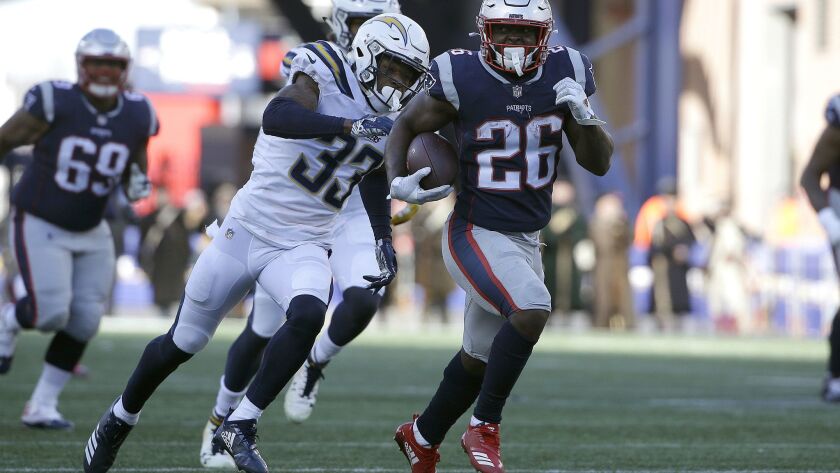 Patriots running back Sony Michel (26) runs away from Chargers safety Derwin James during Sunday's playoff game in Foxborough, Mass. Michel rushed for 129 yards and three touchdowns.
