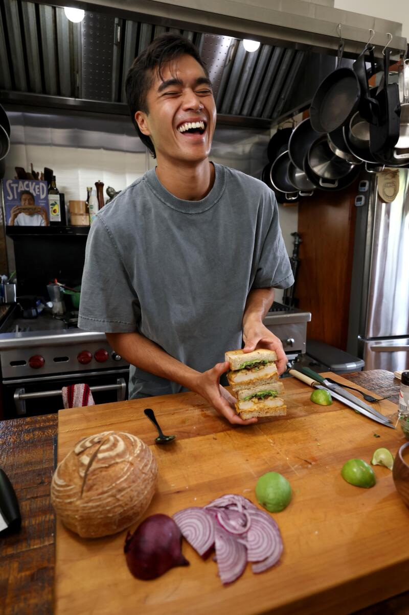 Owen Han laughing in his kitchen, sandwich ingredients in front of hiim