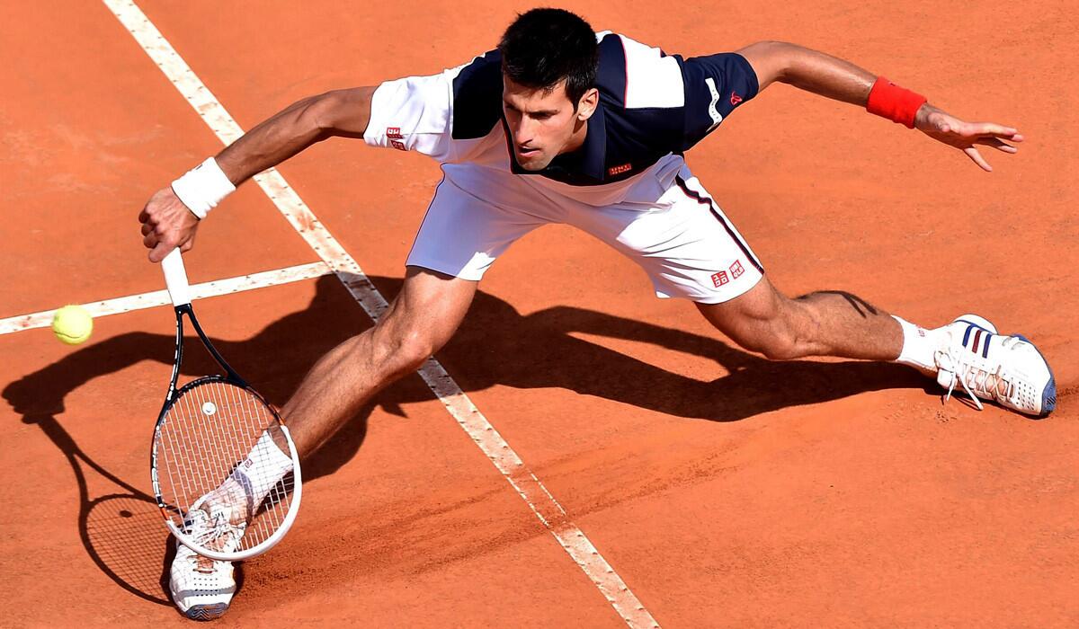 Novak Djokovic slides into a volley during his three-set victory over Milos Raonic in a semifinal of the Italian Open on Saturday.