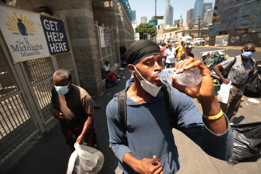 Los Angeles, CA - July 26: The Midnight Mission on Tuesday, July 26, 2022 in Los Angeles, CA. Rieyely Miller, 19, consumes a whole bottle of water without hesitation that he received outside The Midnight Mission in Downtown Los Angeles. The Midnight Mission gives food, water and various beverages to Skid Row residents three times a day. The Mission recently sent out a memo that due to the drought they are running out of water which sheds a different light on a drought story. (Al Seib / For the Los Angeles Times)